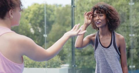 African american women high-fiving on outdoor court after fitness training session