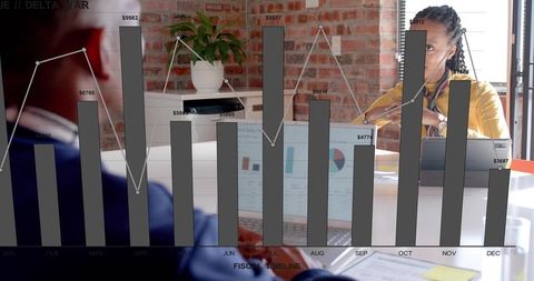 Colleagues reviewing monthly financial bar and line chart overlay on laptop, modern office