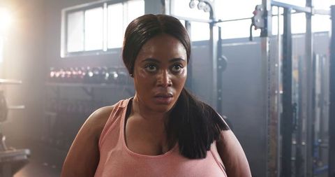 African American woman lifting dumbbell in gym showing focus, determination and strength
