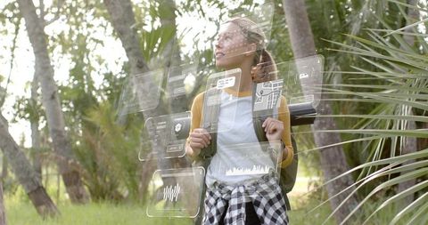 Young woman hiking in palm grove exploring augmented reality navigation panels outdoors