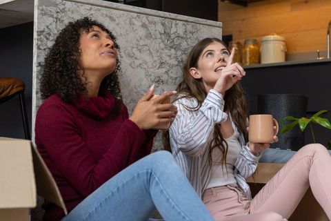 Happy friends unpacking together at new home's modern kitchen counter
