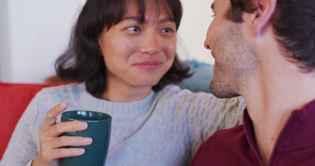 Image of back view of happy diverse couple sitting on sofa and drinking coffee - Download Free Stock Photos Pikwizard.com