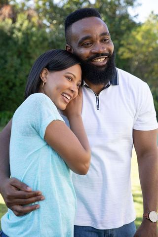 Affectionate Couple Embracing in Park Under Summer Sunlight