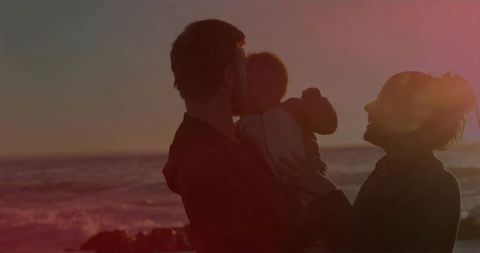 Family bonding in sunset silhouette at serene beachfront