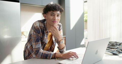 Young Man Typing on Laptop in Modern Minimalist Kitchen