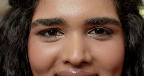 Closeup portrait adult woman looking into camera showing glossy lips smoky eyeliner and curls