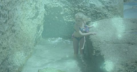 Child exploring tide pools on rocky shore