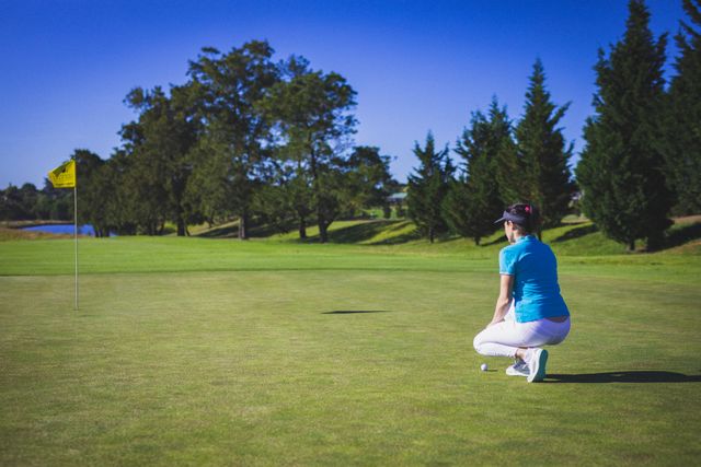 Rear view of caucasian woman keeping golf ball on grass at golf course. sports and active lifestyle concept.