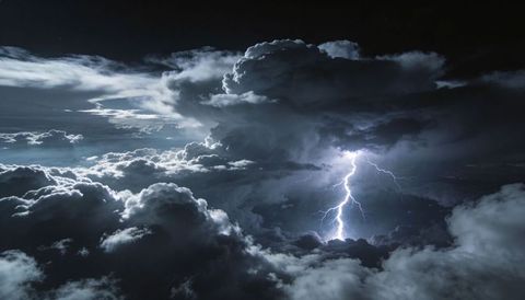 Nocturnal lightning striking towering cumulonimbus above dramatic cloudscape