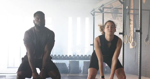 Diverse athletes lifting kettlebells in urban gym environment