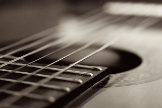 Close-up of acoustic guitar strings and soundhole in sepia tone. Ideal for music and instrument-related content, musician promotions, or artistic decor. Can symbolize melody, creativity, and passion for music.
