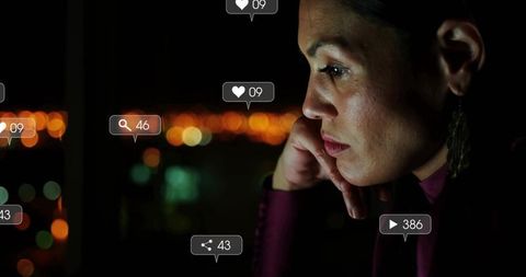 Adult woman gazing out window at night with floating social media icons, urban city bokeh
