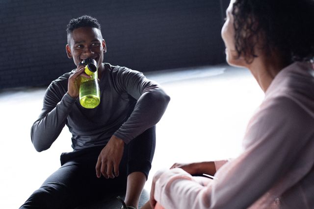 African american man and woman sitting resting drinking water and talking in empty building. urban fitness healthy lifetyle.
