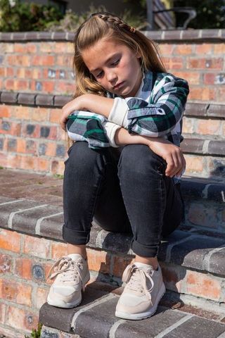 Contemplative Child Sitting on Brick Steps in Sunshine
