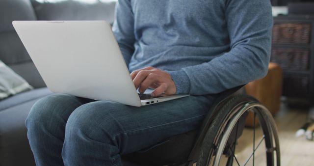 Close-up of person seated in wheelchair using laptop on their lap, suggesting active involvement in work or personal tasks. Suitable for articles or advertisements focusing on accessibility, remote work, or technology support. Useful in promoting inclusive work environments, tools for people with disabilities, or mobility aids.