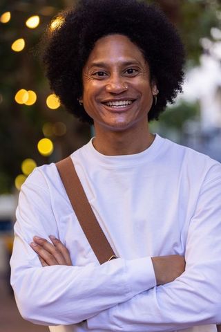 Confident african american man smiling at dusk with crossbody strap and piercings
