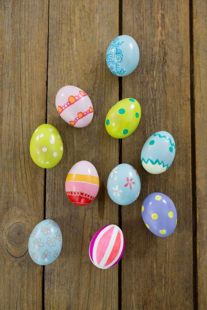 Brightly painted Easter eggs with various patterns and colors arranged on a rustic wooden surface. Ideal for use in holiday-themed designs, spring celebration promotions, Easter event invitations, and festive decoration ideas.