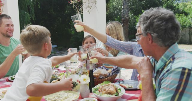 Family gathered around a table enjoying an outdoor meal and toasting with drinks. Perfect for depicting moments of celebration, bonding, and togetherness. Ideal for use in advertisements, brochures, and blog posts that emphasize family values, outdoor activities, and festive occasions.