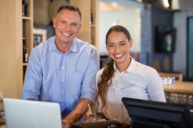 Manager and bartender smiling at bar counter, showcasing teamwork and hospitality in a restaurant or bar setting. Ideal for use in business, hospitality, and customer service promotions, as well as for illustrating teamwork and professional environments.