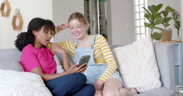 Two Young Women Relaxing on Couch and Looking at Smartphone Together - Download Free Stock Images Pikwizard.com