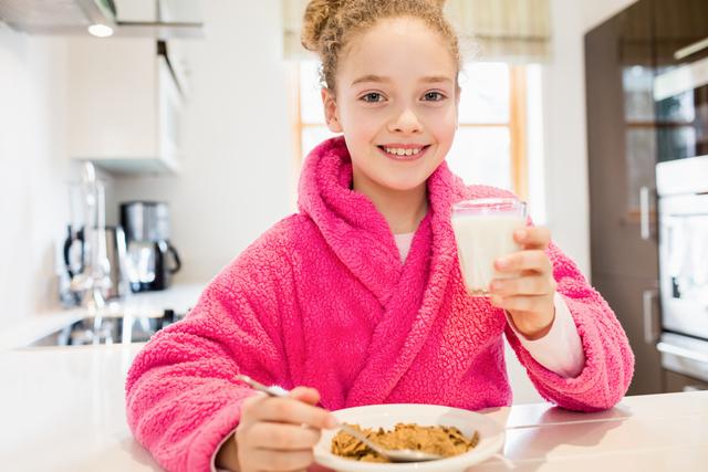 Cute girl having breakfast in kitchen - Download Free Stock Photos Pikwizard.com
