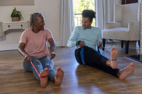 Senior duo exercising with resistance bands in sunlit living room for mobility