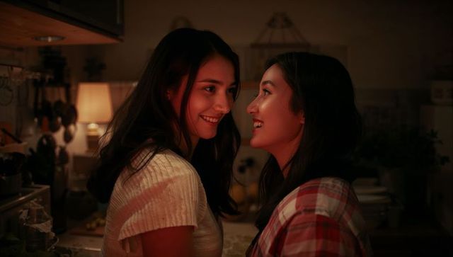 Smiling asian couple sharing intimate kitchen moment with warm ambient lighting