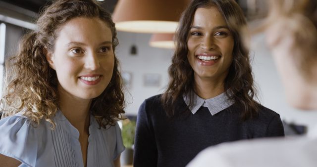 Two women smiling in a casual indoor environment - Download Free Stock Images Pikwizard.com