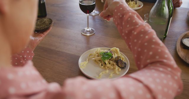 Person Seasoning Pasta at Dinner Table with Wine - Download Free Stock Images Pikwizard.com