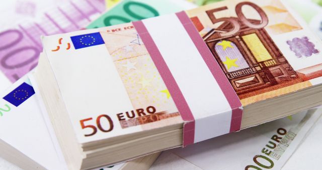 Stacks of 50 and 100 Euro banknotes are displayed, showcasing the currency of the Eurozone, with copy space. The image represents financial themes such as wealth, savings, investment, or European economy.