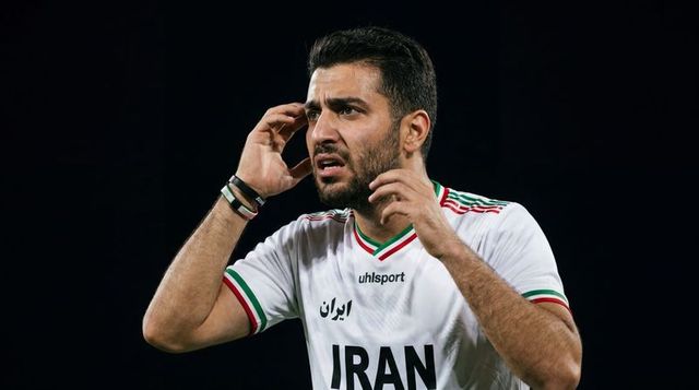 Concentrating iranian footballer reacting during night match wearing white national jersey