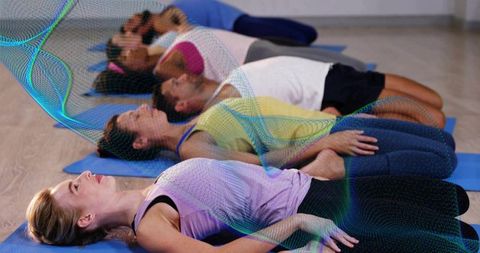 Adults lying in restorative yoga practicing deep breathing for relaxation on blue mats