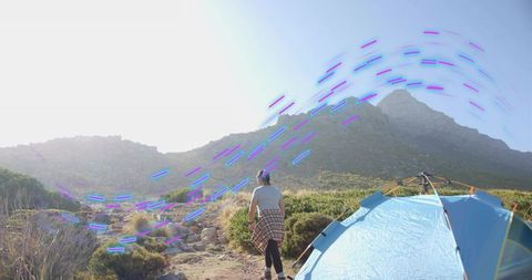 Hiker Exploring Wilderness with Blue Dome Tent and Scenic Mountains
