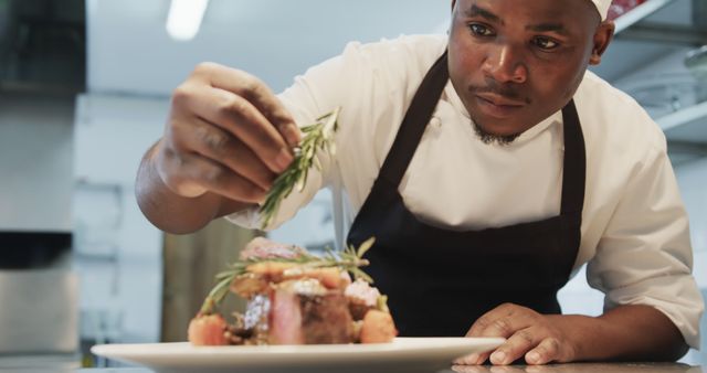 Chef garnishing rosemary on gourmet dish in restaurant kitchen. Ideal for depicting professional culinary arts, fine dining, gourmet cooking, andupscale restaurant environments. Perfect for use in cooking magazines, culinary blogs, chef training materials, and restaurant promotional content.