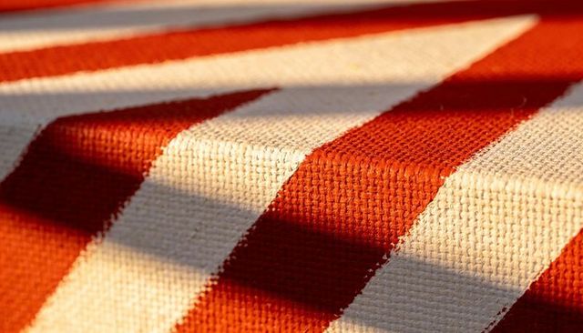 Macro closeup of red and white woven textile showing fibers, ridges and striped shadows