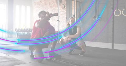 Athletes resting and hydrating after intense crossfit session in industrial gym with rings