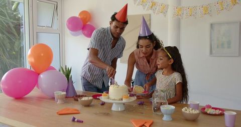 Family Celebrating Birthday at Home with Cake and Party Hats