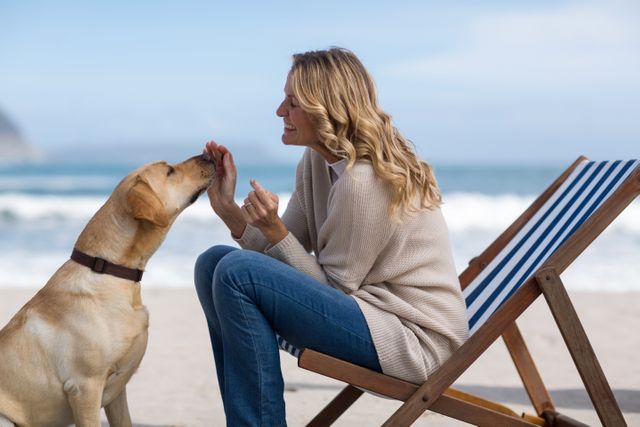 Mature woman petting her dog on the beach