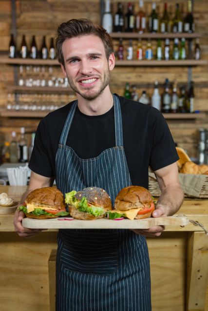 Portrait of waiter holding food at counter in cafÃ©