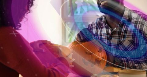 Couple carving pumpkin together at home crafting smiling jack-o'-lantern for halloween