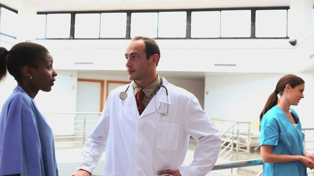 Healthcare professionals are discussing patient care in well-lit hospital corridor. Doctor and nurses collaborating highlight teamwork. Suitable for medical, health industry, or teamwork illustrations.