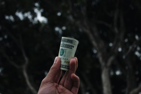 Hand Holding Rolled US Dollar Banknotes Outdoors