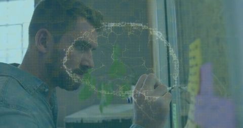 Senior man writing on glass partition during modern office brainstorming with sticky notes