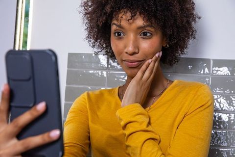 Woman Checking Skin in Bathroom Using Smartphone