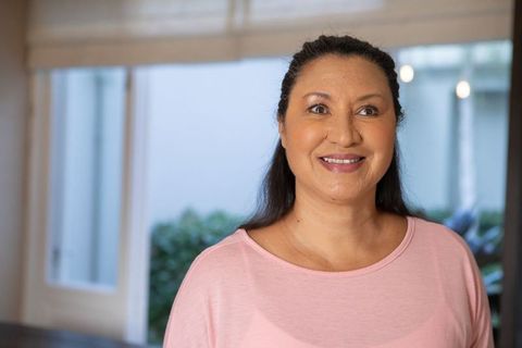 Smiling woman in bright living room with white blinds