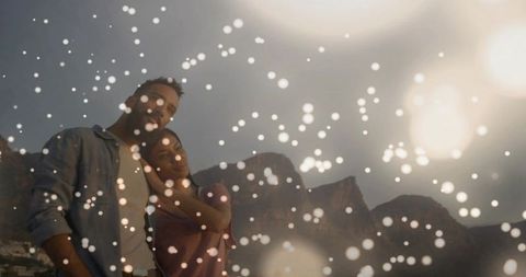 Romantic couple leaning at mountain viewpoint at dusk with bokeh lights and silhouette