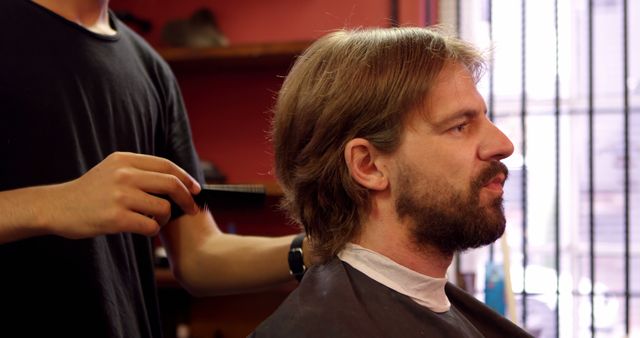 Caucasian man getting a haircut in a barbershop. A professional barber is styling the man's hair, ensuring a neat appearance.