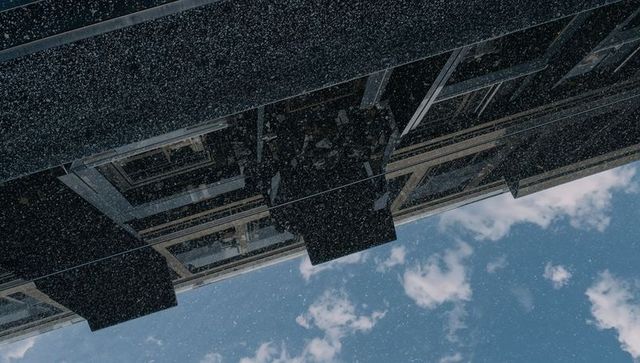 Diagonal glass facade slanting across sky with reflective panels, box balconies, snow