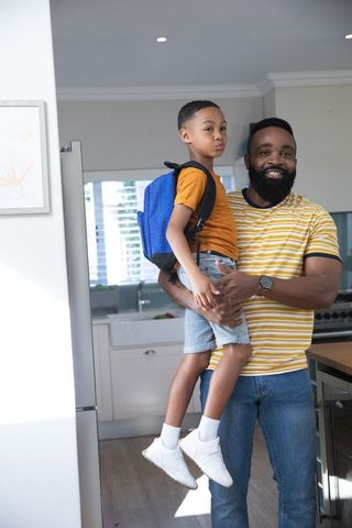 Father and Son Bonding in Kitchen with School Backpack