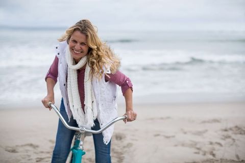 Smiling Woman Enjoying Bicycle Ride on Shoreline